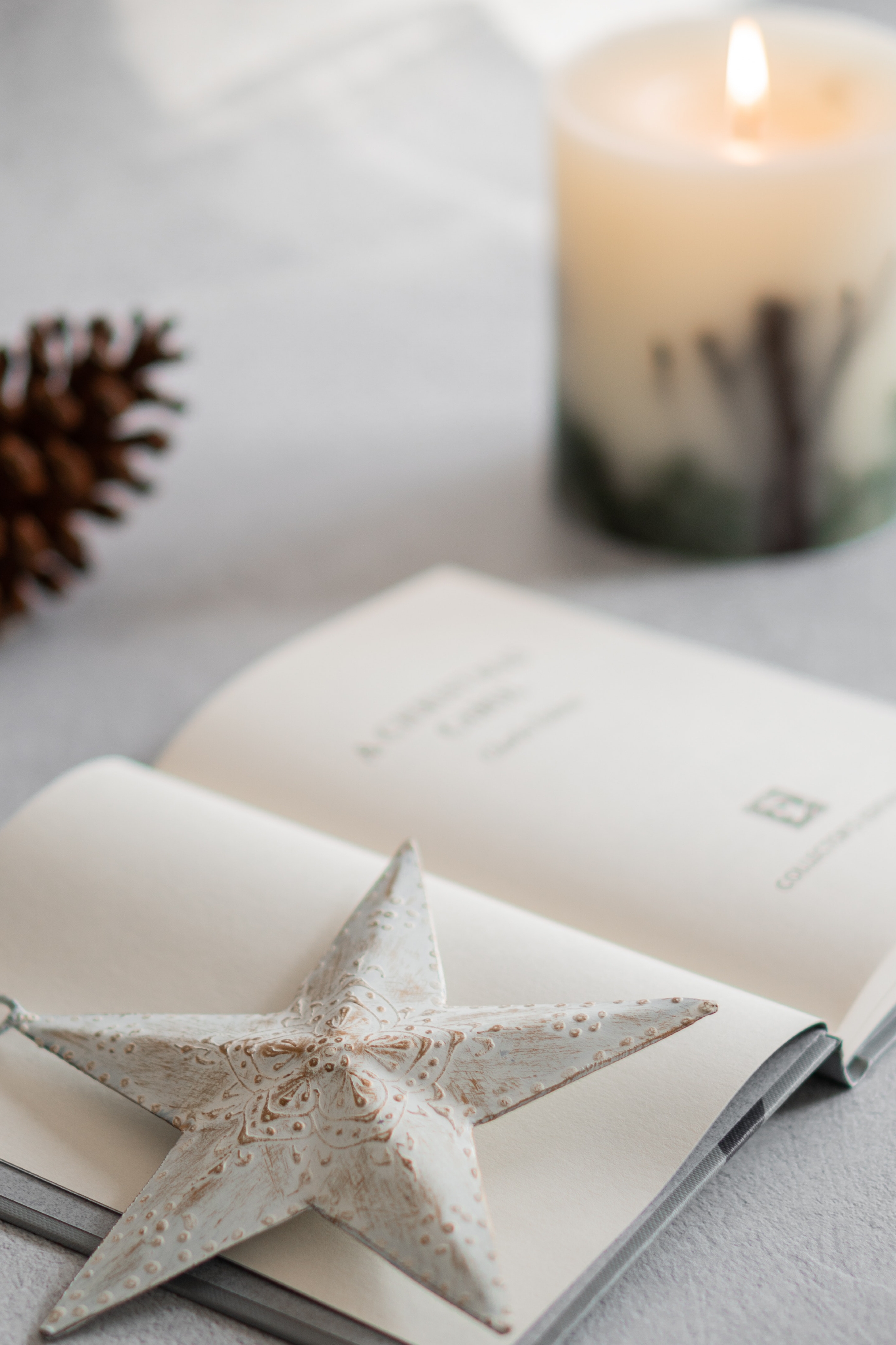 Estrella decorativa sobre un libro abierto con vela encendida al fondo